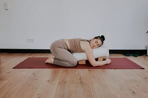 Frau in Yin Yoga Position mit Yogabolster und Yogablöcken
