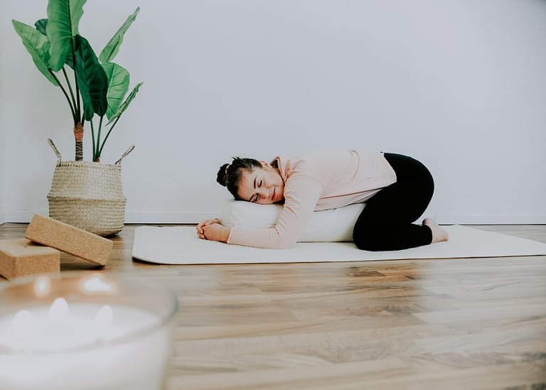 Frau liegt entspannt auf einem Yogabolster